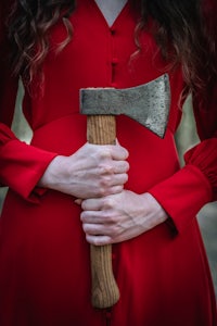 a woman in a red dress holding an axe