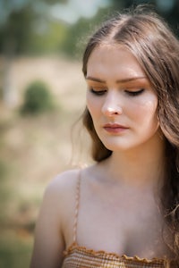 a young woman with long hair standing in a field