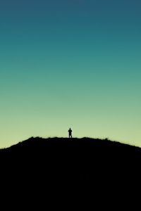 a silhouette of a person standing on top of a hill