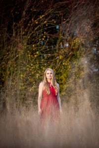 a woman in a red dress standing in tall grass